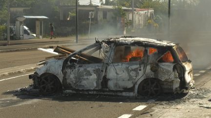 Une voiture incendi&eacute;e le 17 septembre 2024 &agrave; Fort-de-France alors que l'&icirc;le fait face &agrave; la col&egrave;re des habitants, accabl&eacute;s par l'envol&eacute;e des prix. (THOMAS THURAR / AFP)