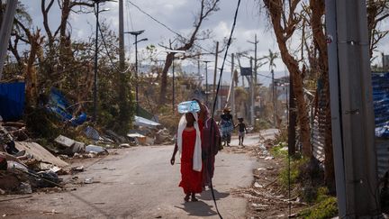 Une femme transporte de l'eau &agrave; Pamandzi (Petite-Terre, Mayotte), le 17 d&eacute;cembre 2024, trois jours apr&egrave;s le passage du cyclone Chido sur l'archipel. (DIMITAR DILKOFF / AFP)