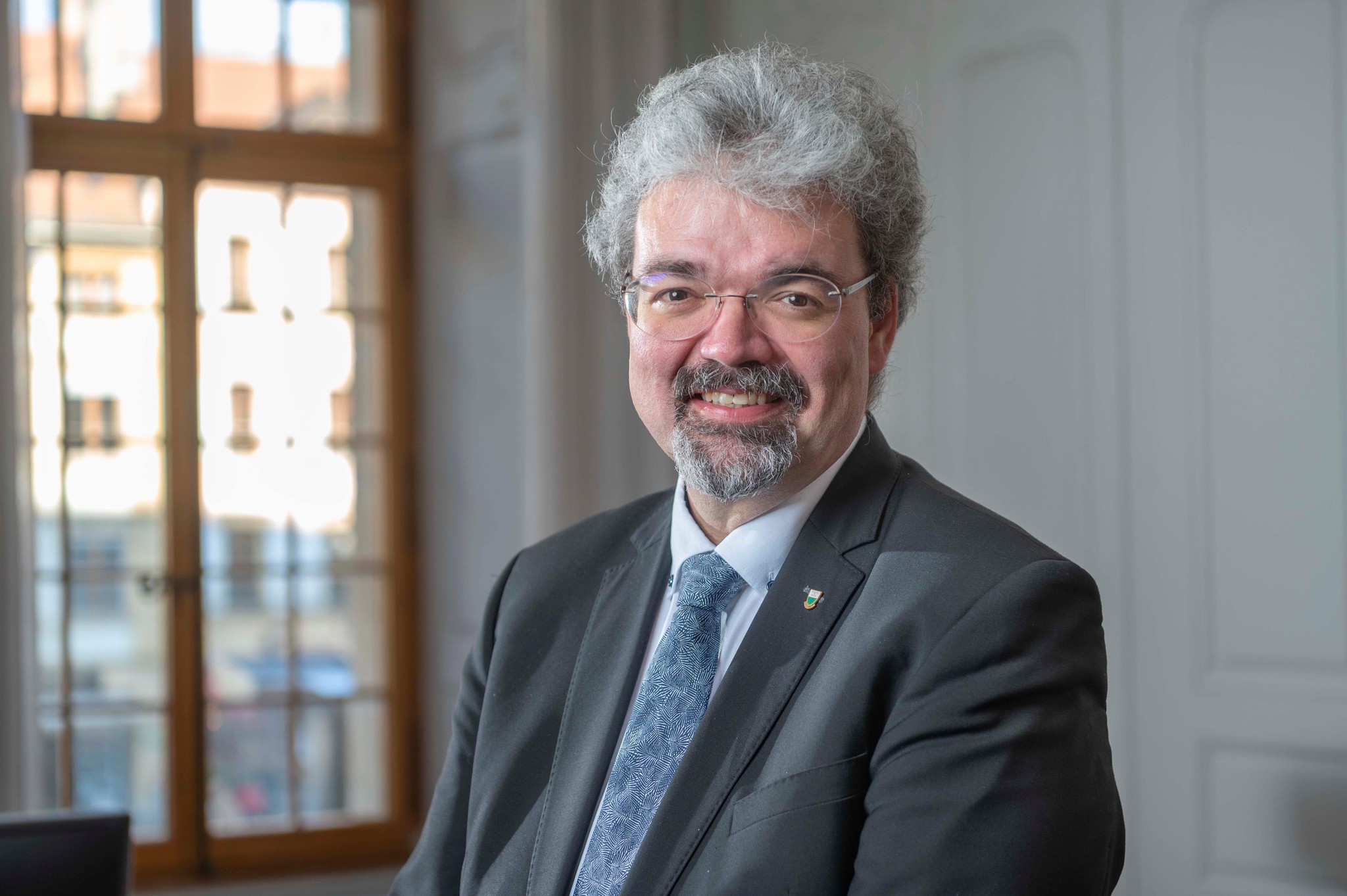 Pierre Dessemontet, le syndic d&rsquo;Yverdon, souriant, en costume, devant une fen&ecirc;tre, &agrave; Yverdon-les-Bains, 19 janvier 2023.